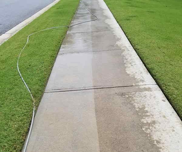 Pressure washing in progress on a residential sidewalk
